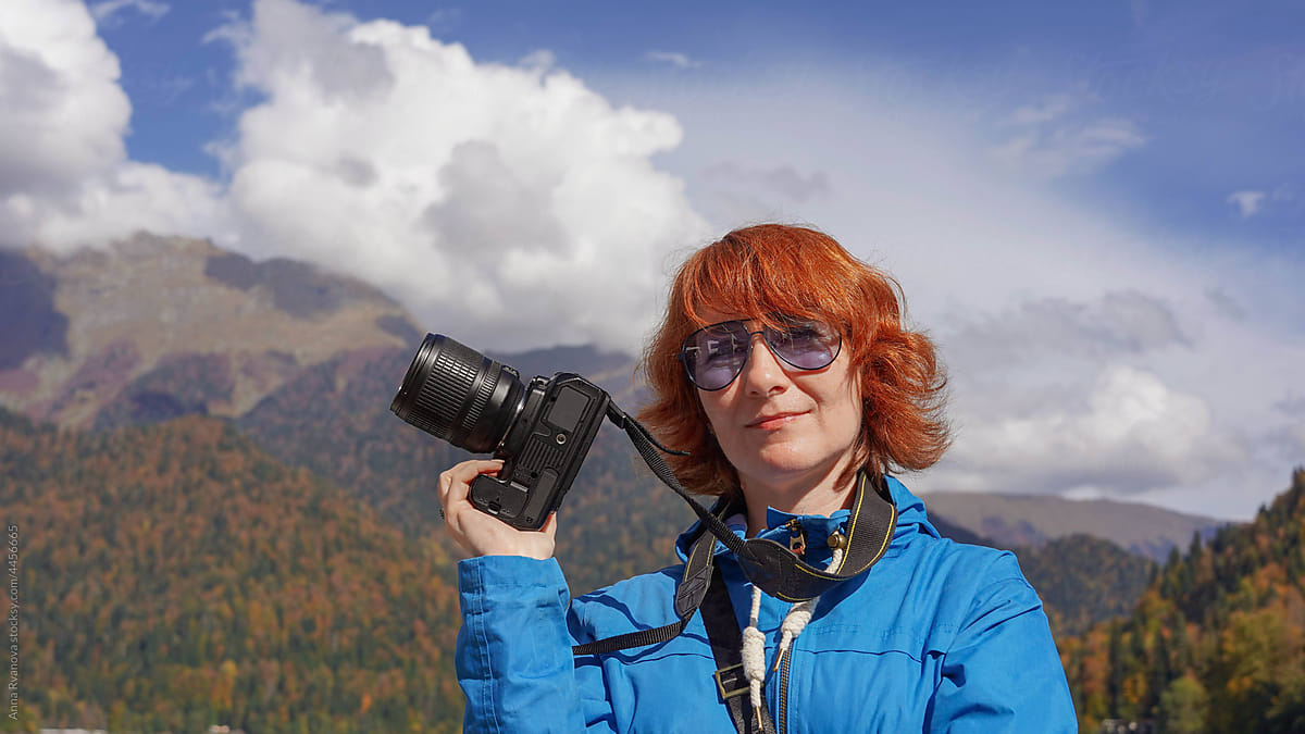 red-haired woman in mountains with camera