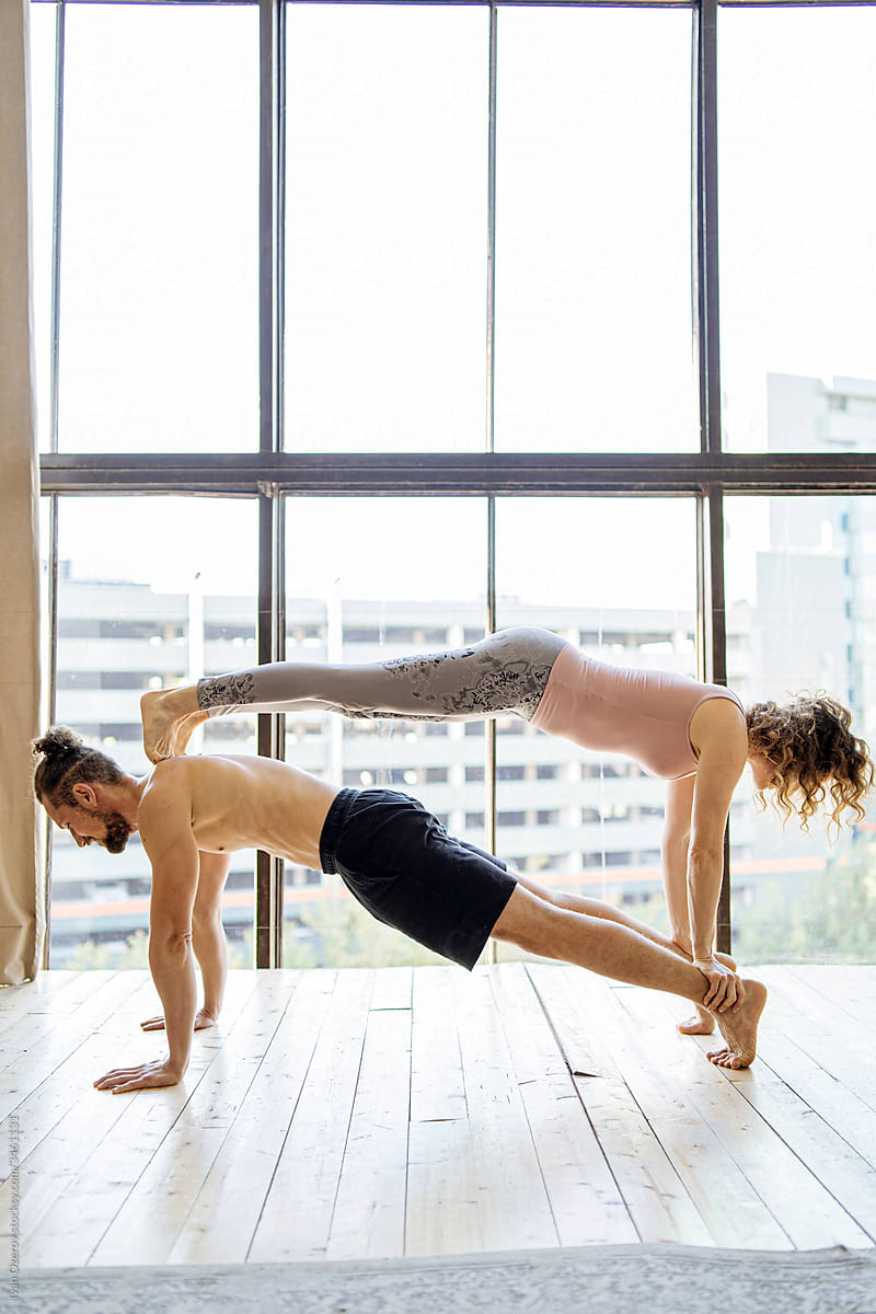 fit man and woman do acro yoga together at home
