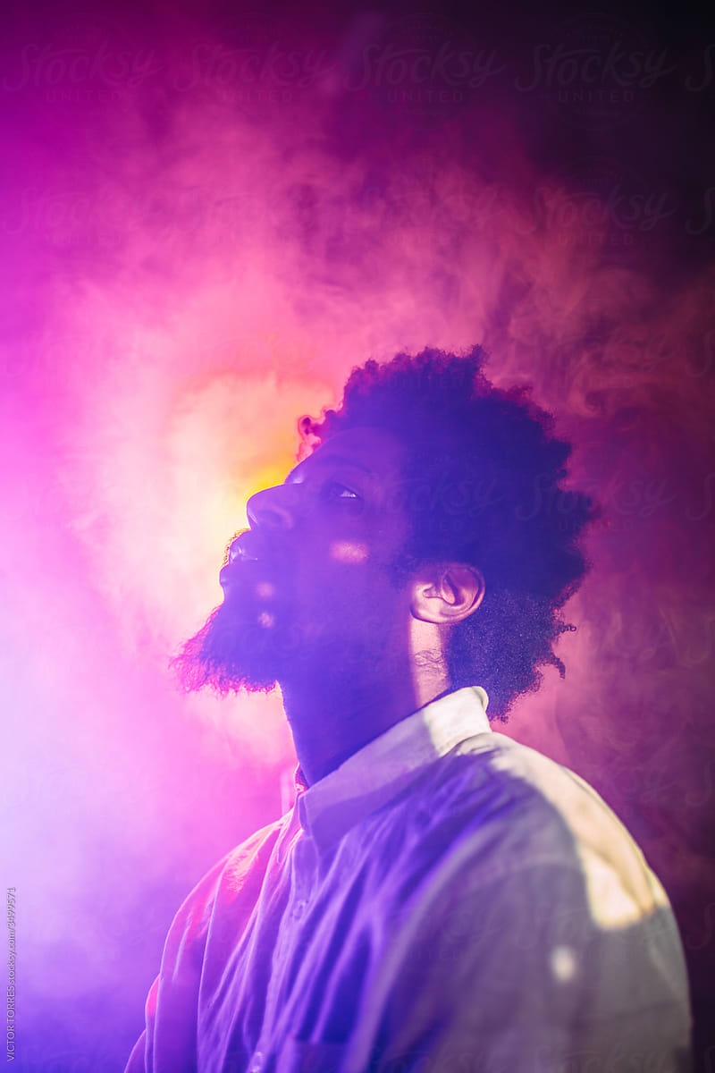 Serious black man in neon light in studio