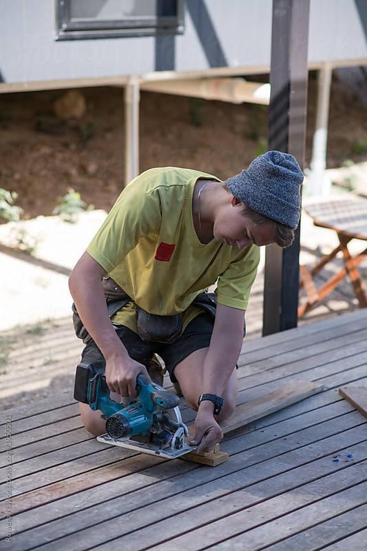 Young apprentice builder using power tools on job