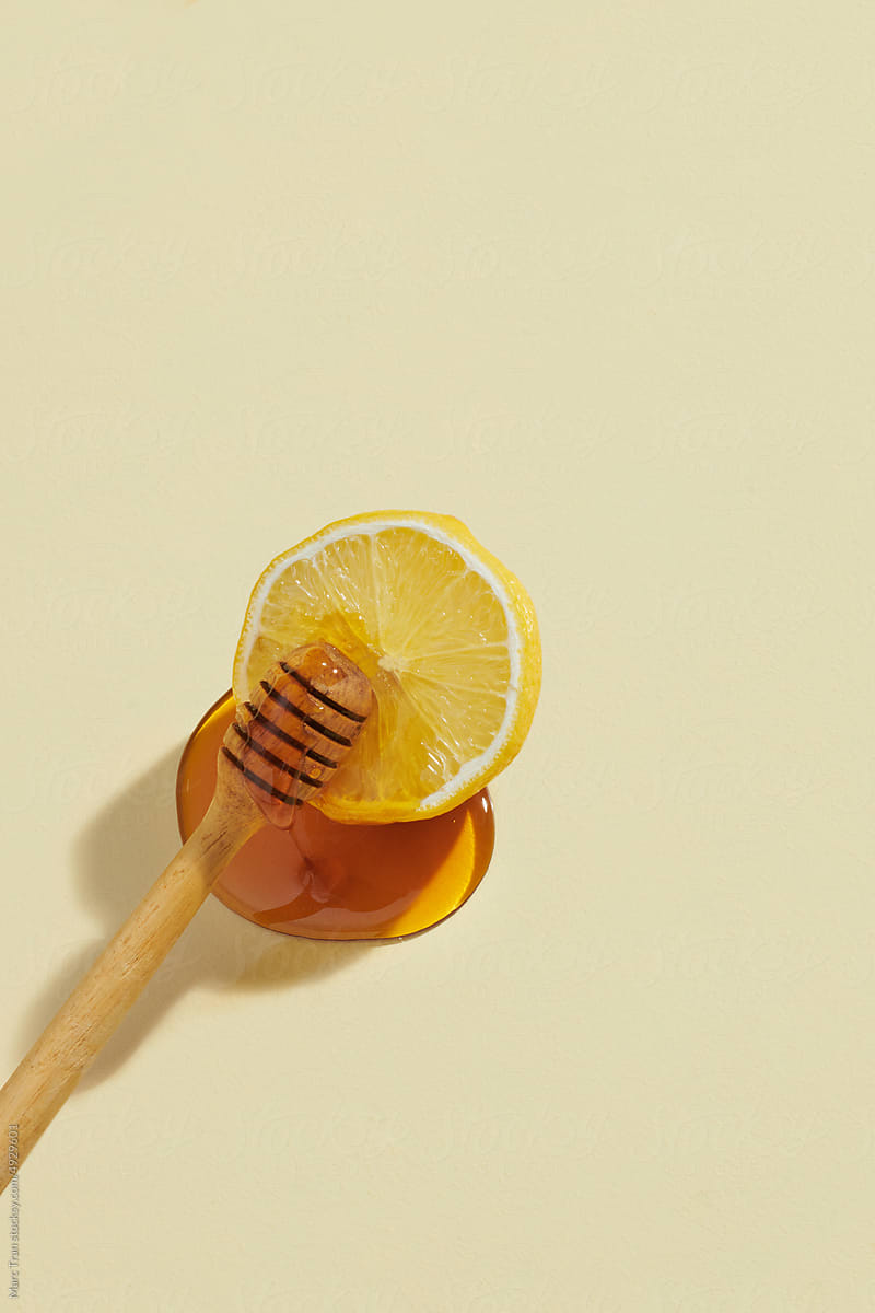 dripping honey on lemons isolated on a light yellow background