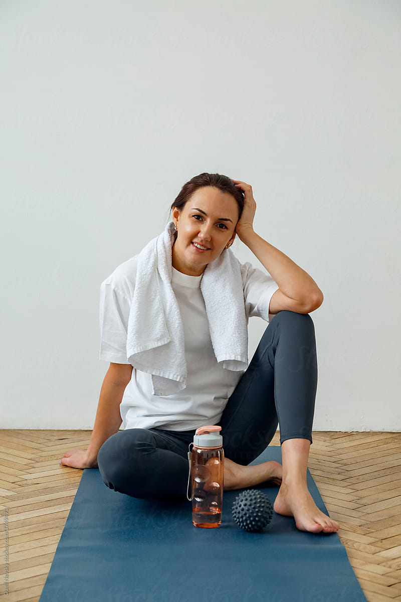 Smiling woman sitting on yoga mat at home