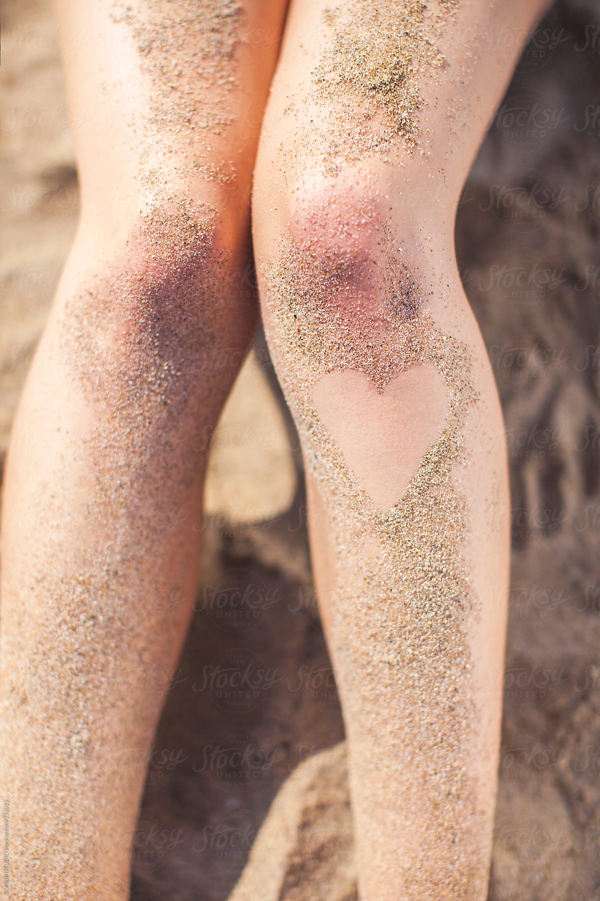 Love heart shaped with beach sand on the legs of a beautiful woman.