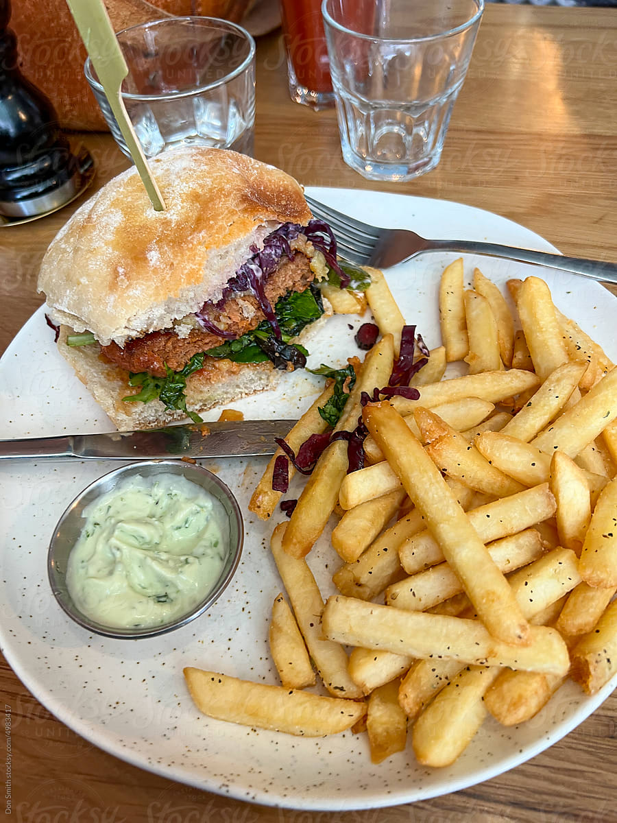 Vegan burger partly eaten with chips