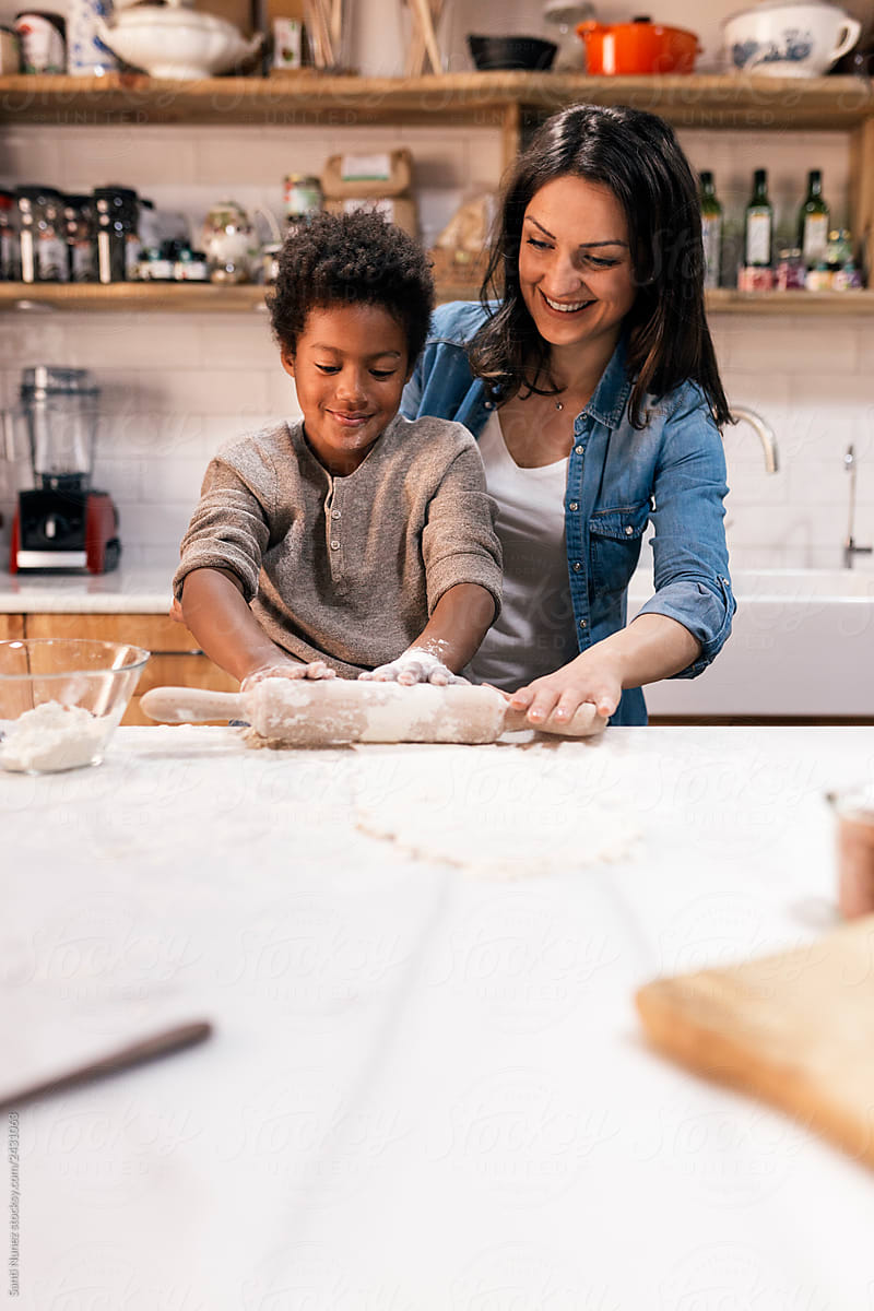 Black child and woman at table with rolling pin and different ingredients