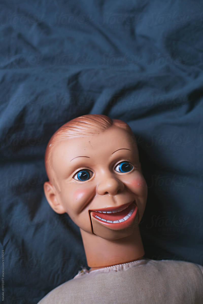 Creepy talking doll lying on a bed by 