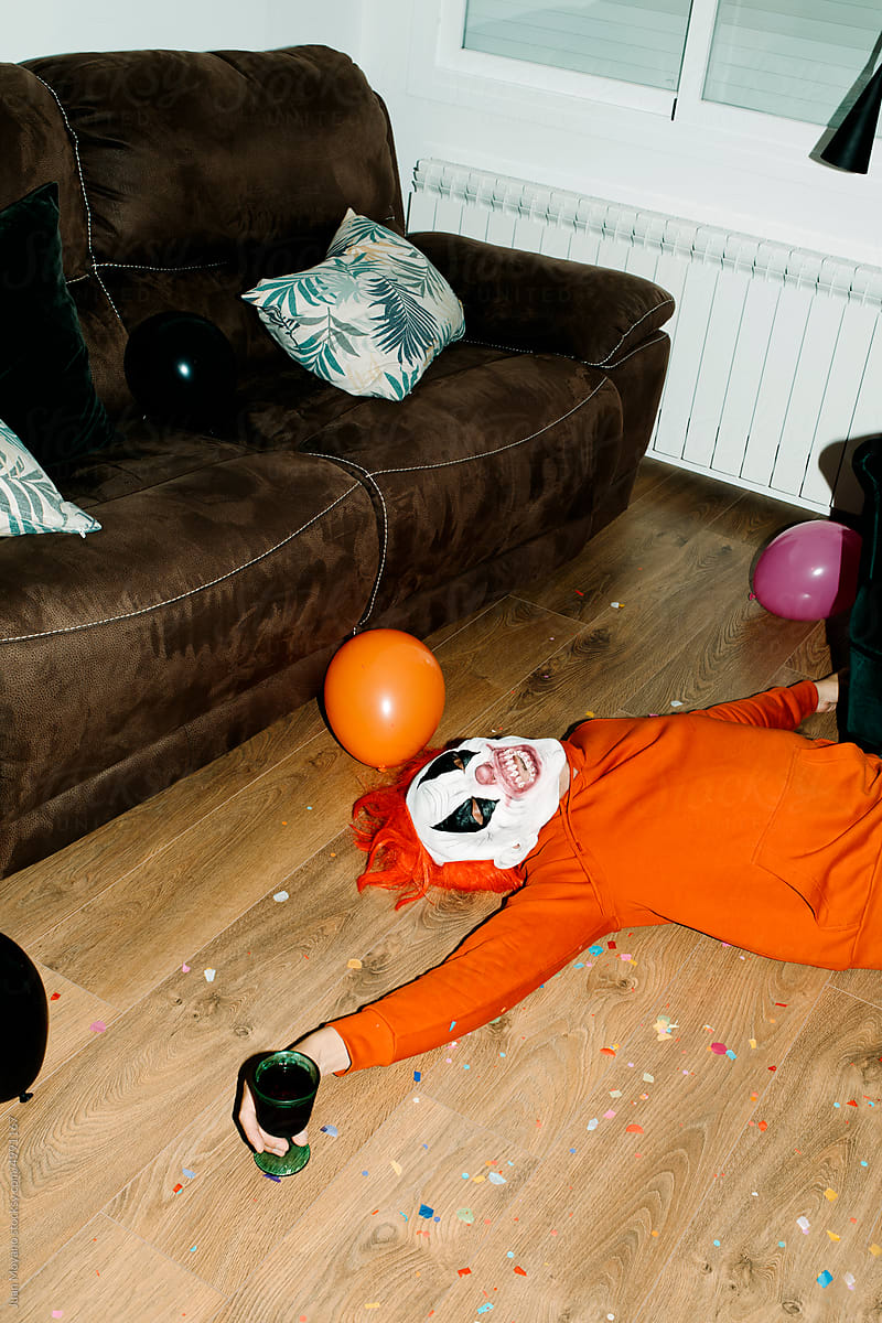 man lying down on the floor wearing a mad clown mask