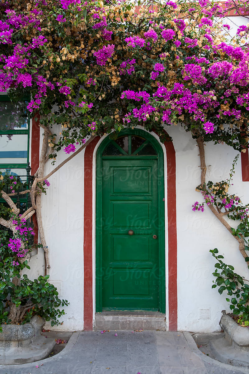Green door under white arch with flowers