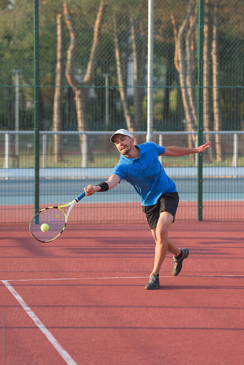 Determined male tennis player hitting the ball with forehand stroke