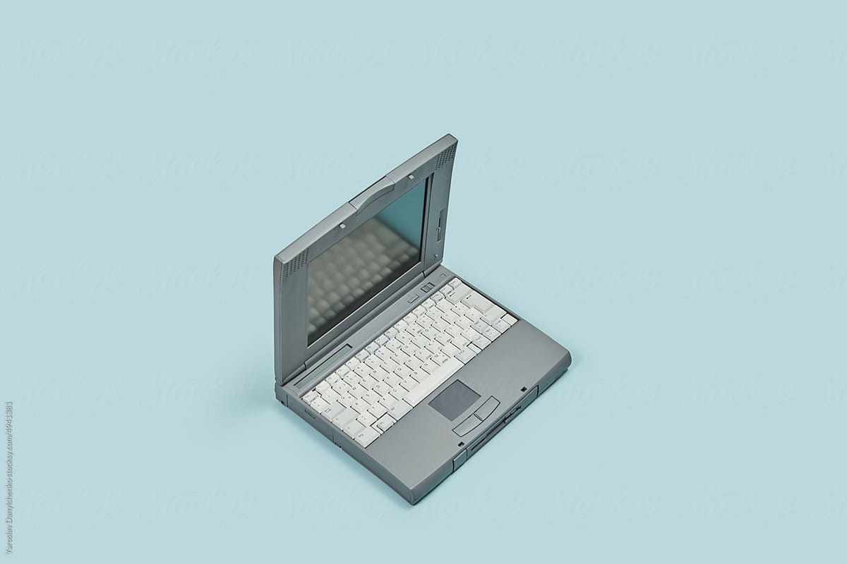 Retro 90s laptop on blue background.