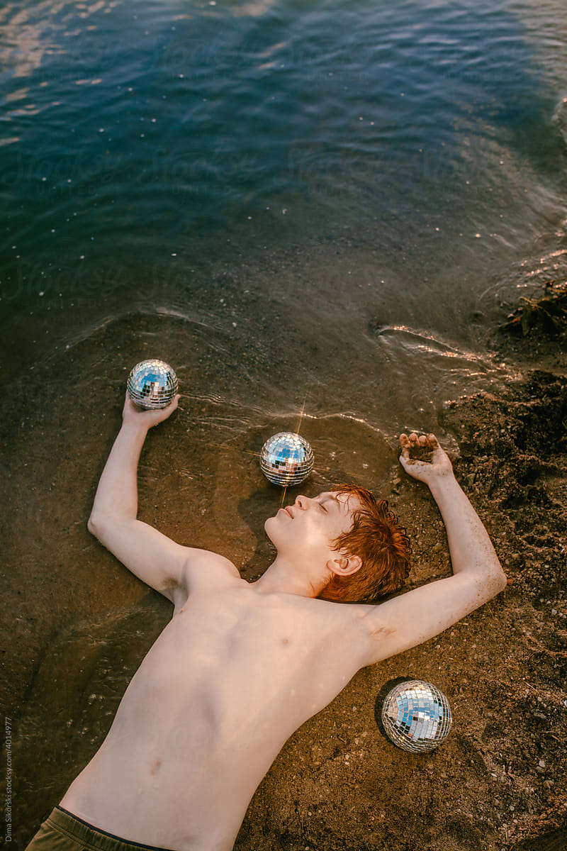 A young man with mirror balls at sunset