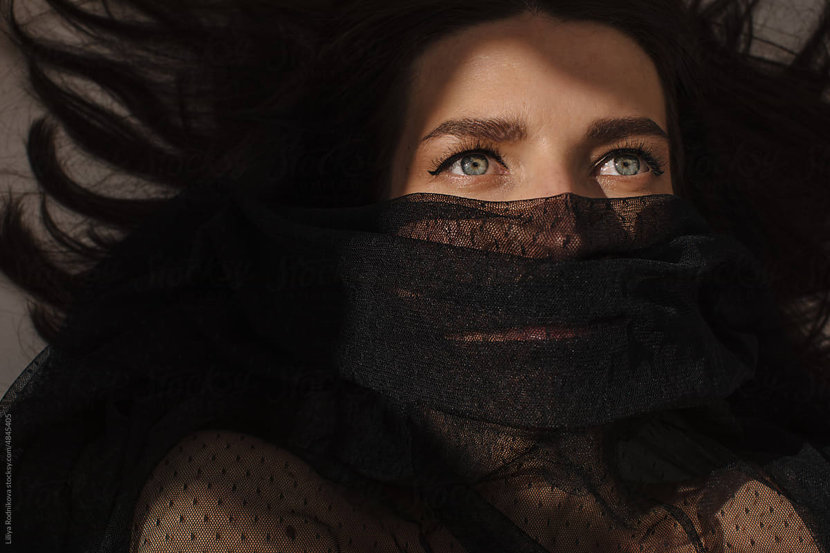Brunette Woman with blue eyes looking up under black veil