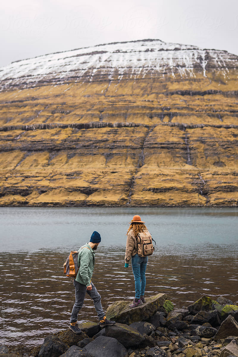 Unrecognizable travelers walking on lake shore