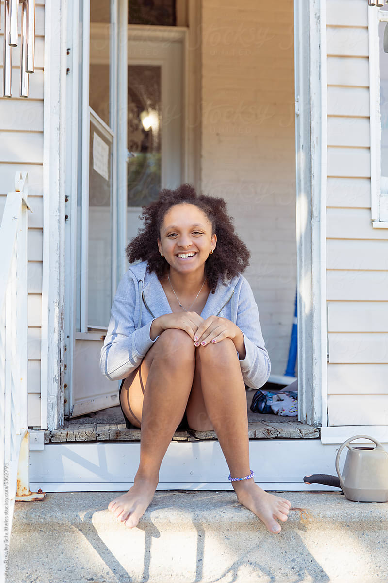 Teenager girl sitting outside on the top stairs of her home