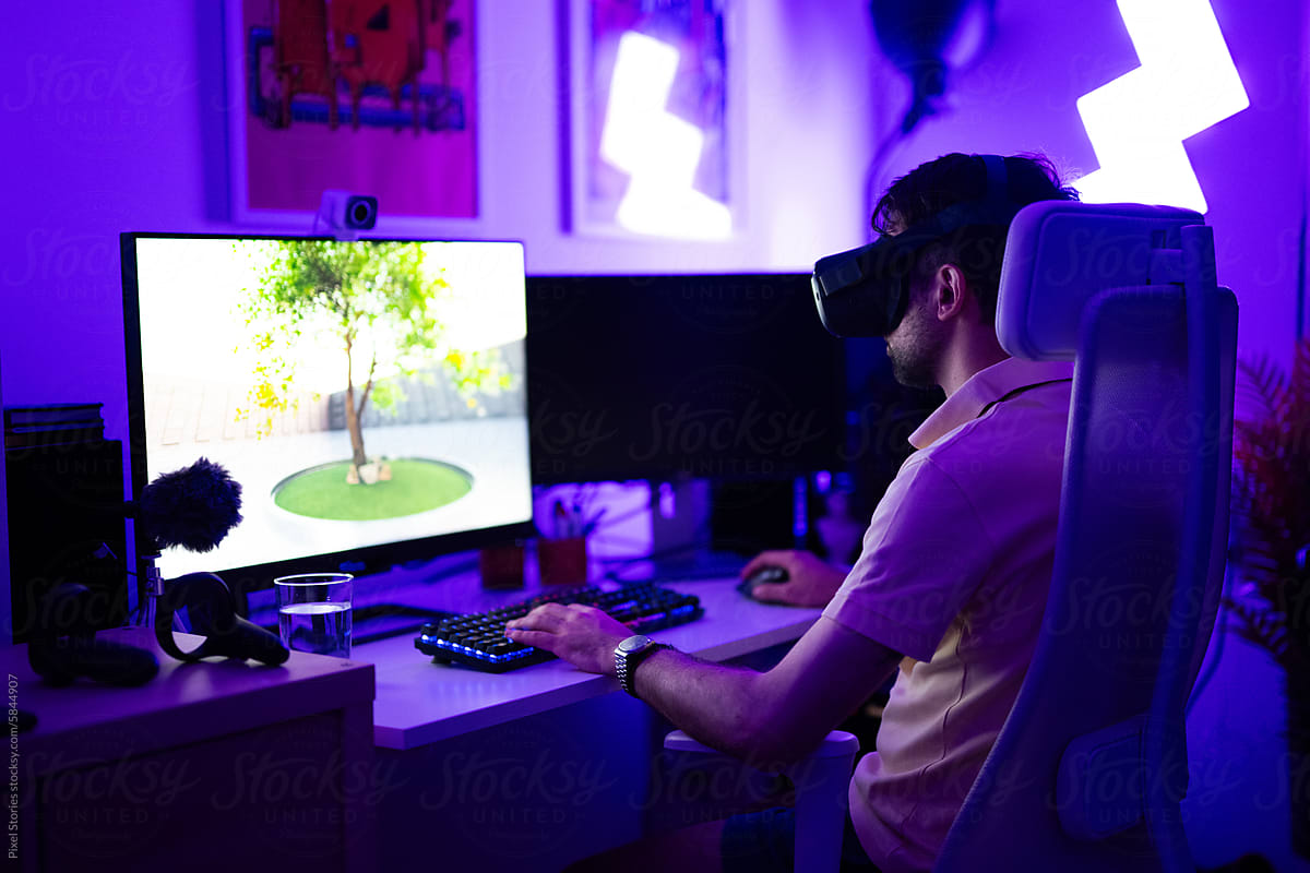 Young adult gamer playing using VR headset on computer PC
