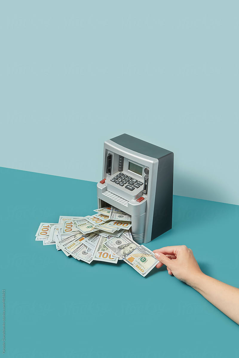 Hand withdrawing dollars in cash machine.