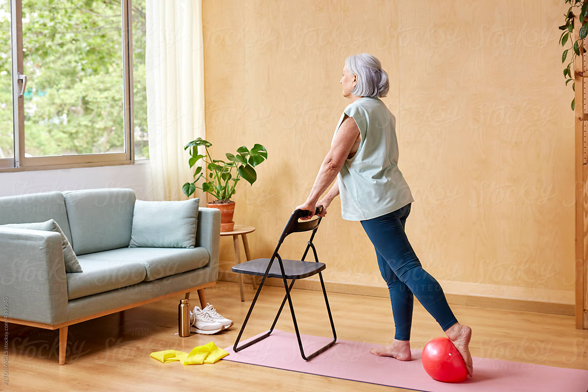 Senior woman exercising with ball and chair