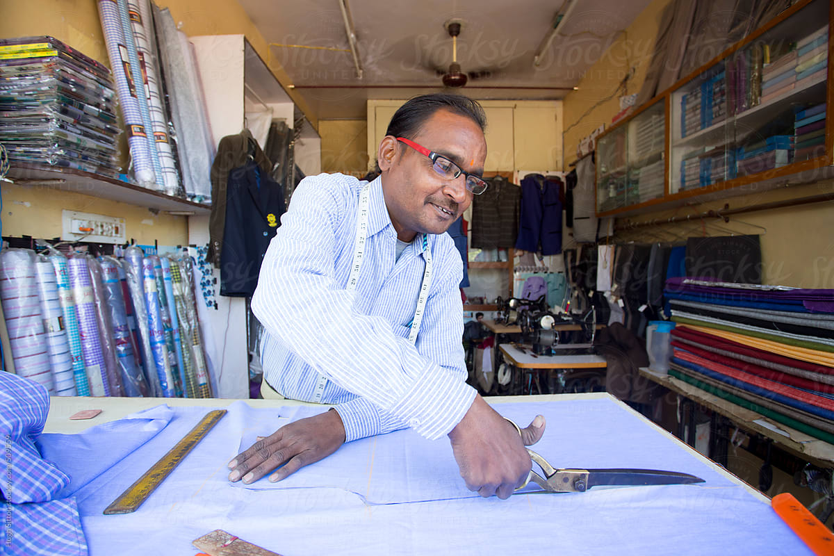 Tailor cutting fabric in his shop. India