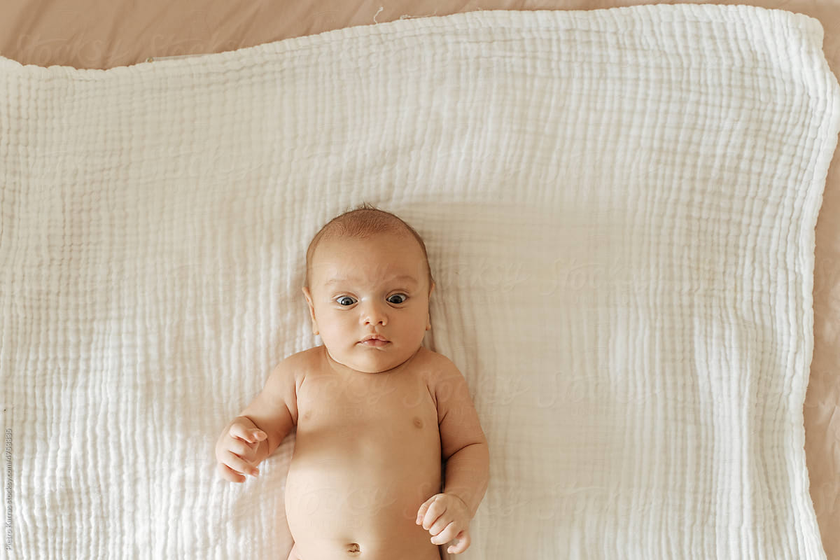 Newborn baby happily lying on a bed