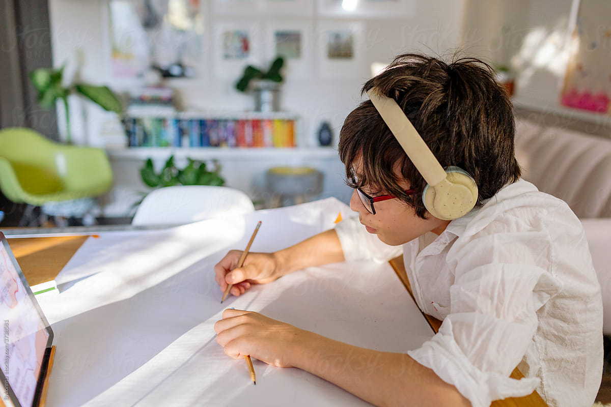 Side view Boy wearing shirt and headphone drawing a map and using a tablet