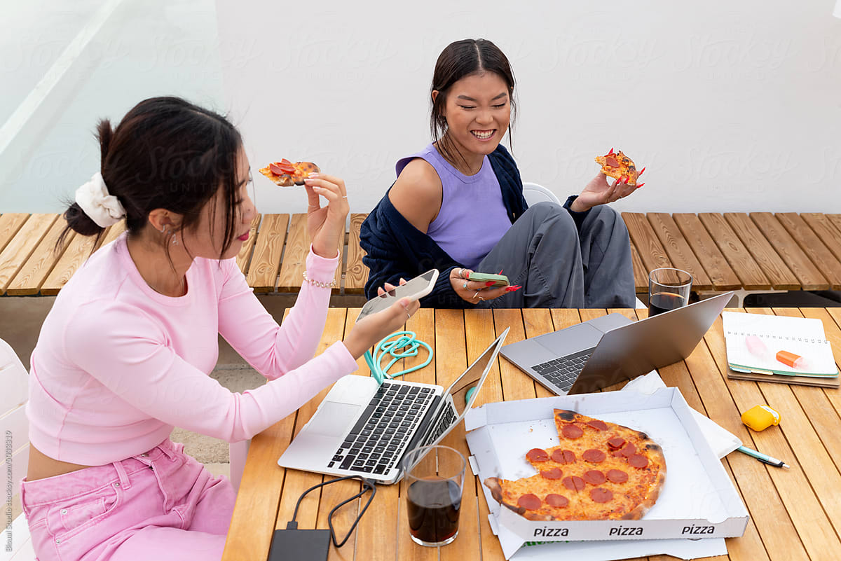 Asian girls studying together and eating pizza