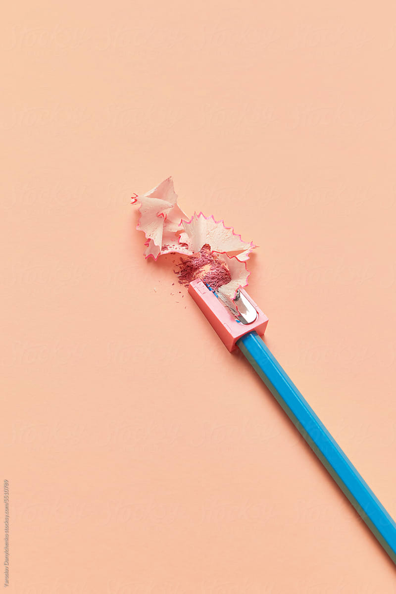 Blue pencil stuck in sharpener with pink shavings.