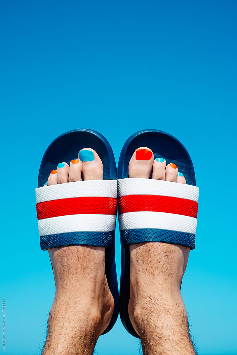 man in sandals with his toenails painted red and blue