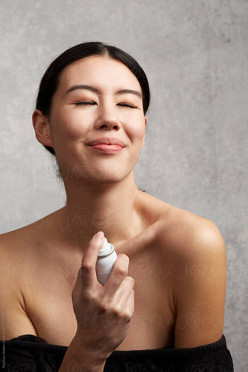 Mixed Race Asian Woman Using Skincare Facial Mist Spray