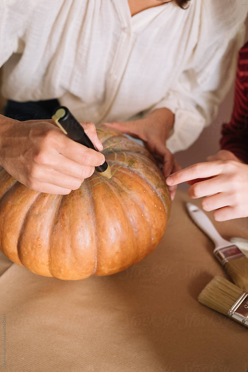 Woman showing a girl how to decorate a pumpkin