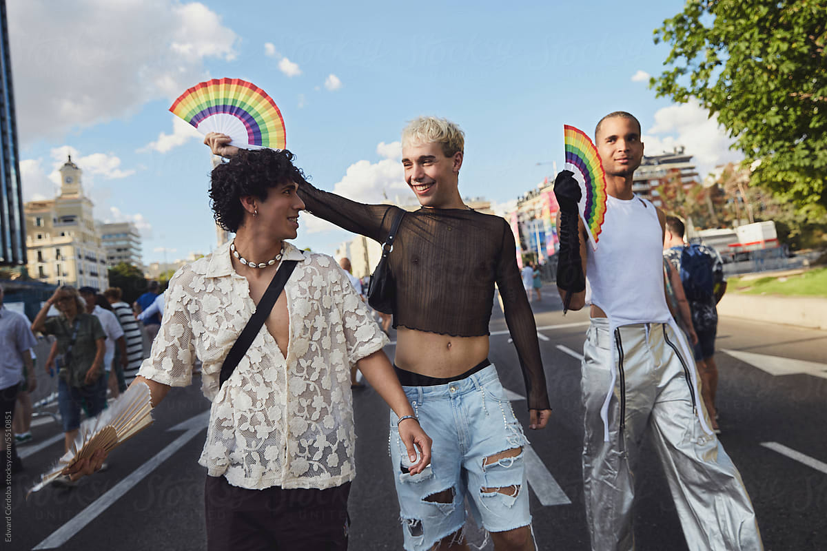 Three queer friends confidently walk down the street during gay pride
