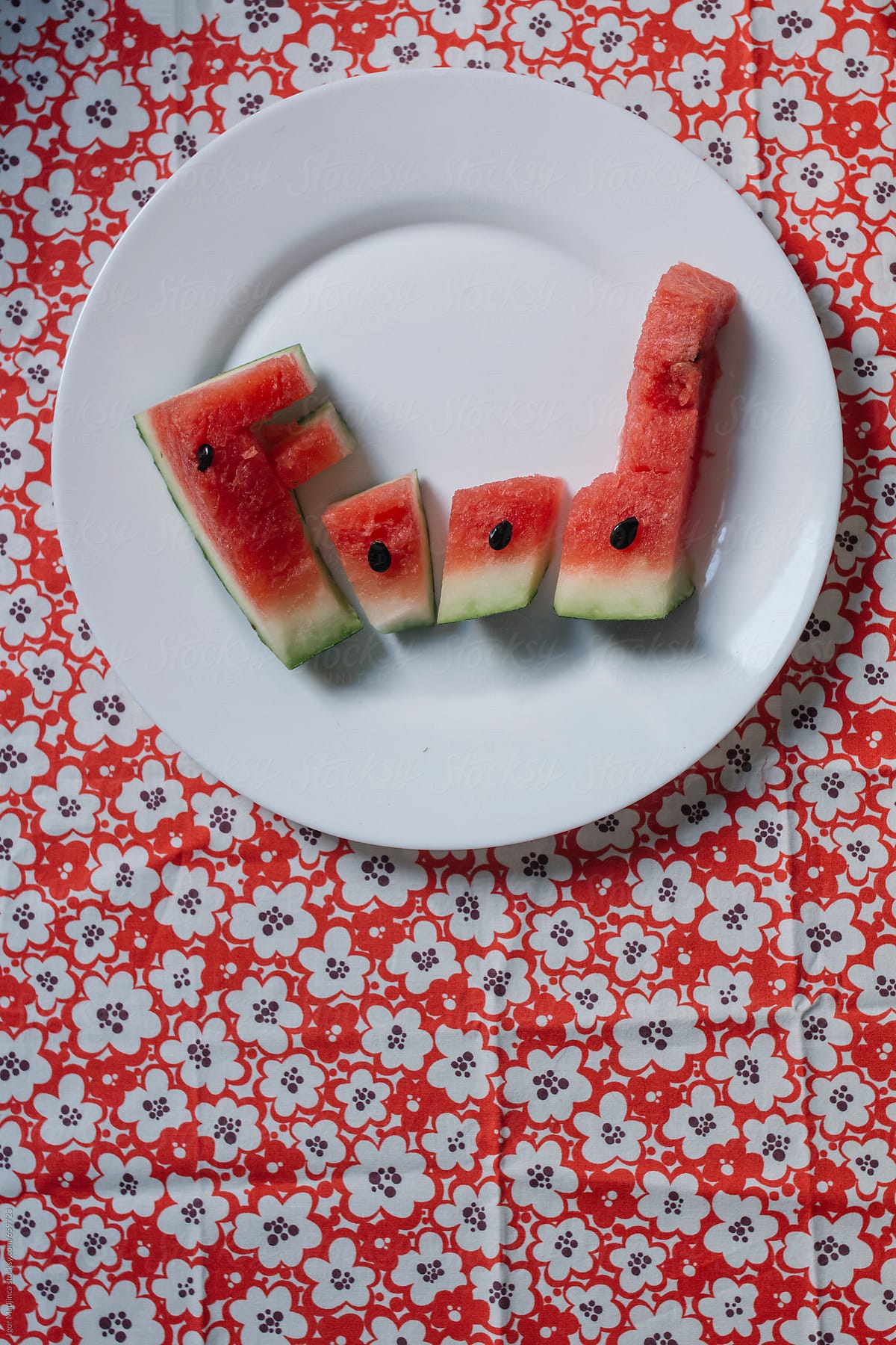 food,  watermelon letters on a white plate on a colorful floral tablecloth