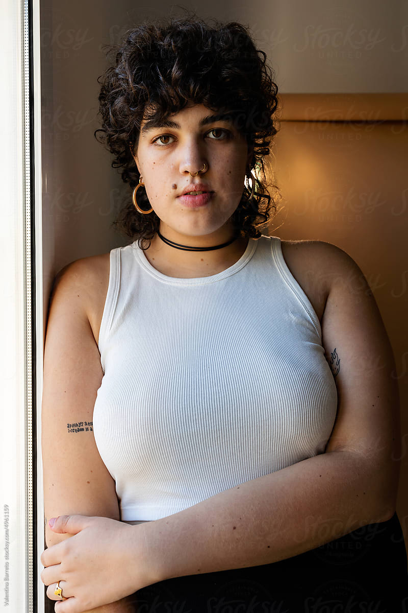 Trans young woman by window portrait