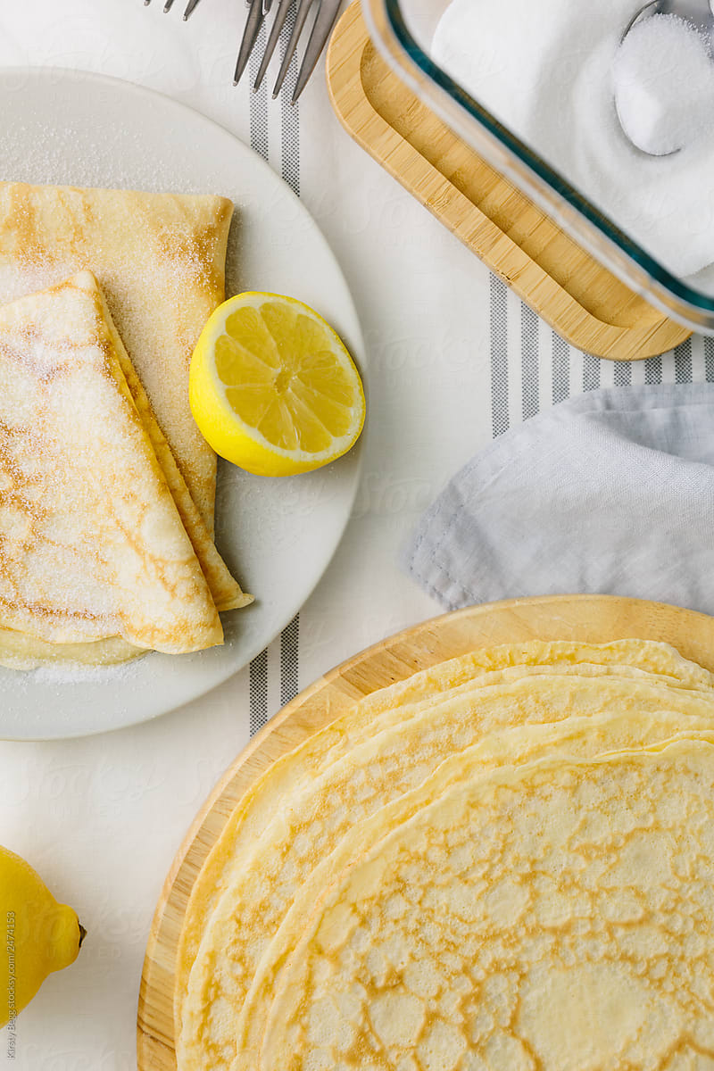 Folded crepes on plate with lemon and sugar