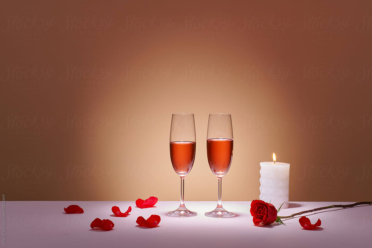 Two glasses of rose wine and red grapes on a colored background.