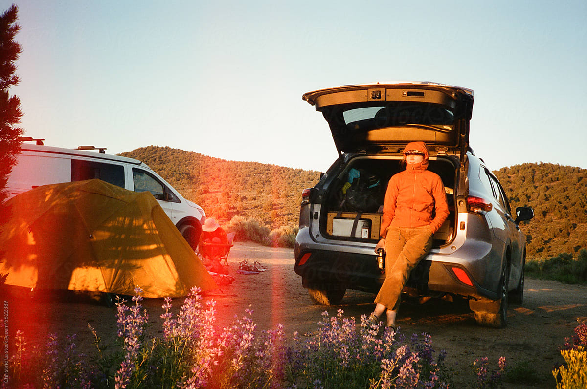Woman standing by car camper at a campsite.