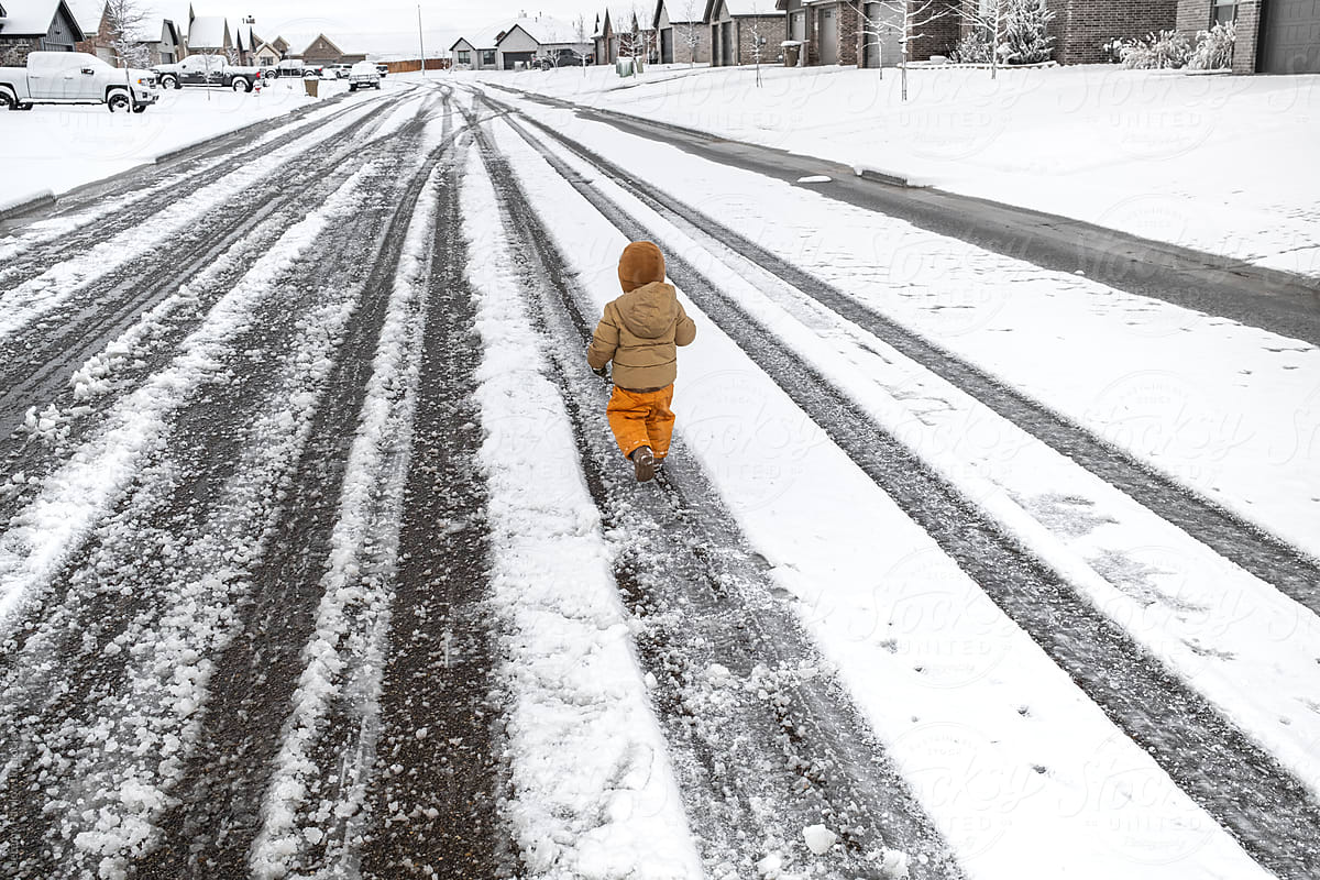 Child Walking Down A Snow Covered Street