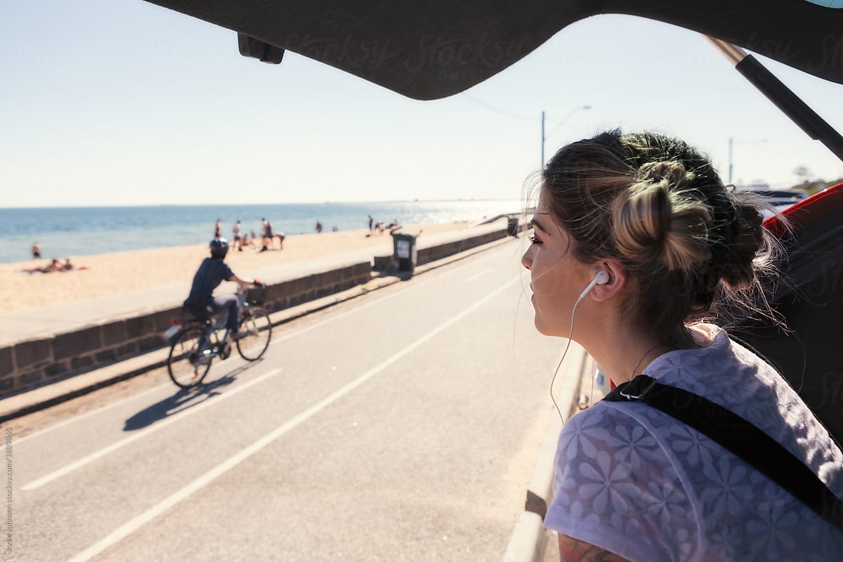 Girl with headphones looking at the beach