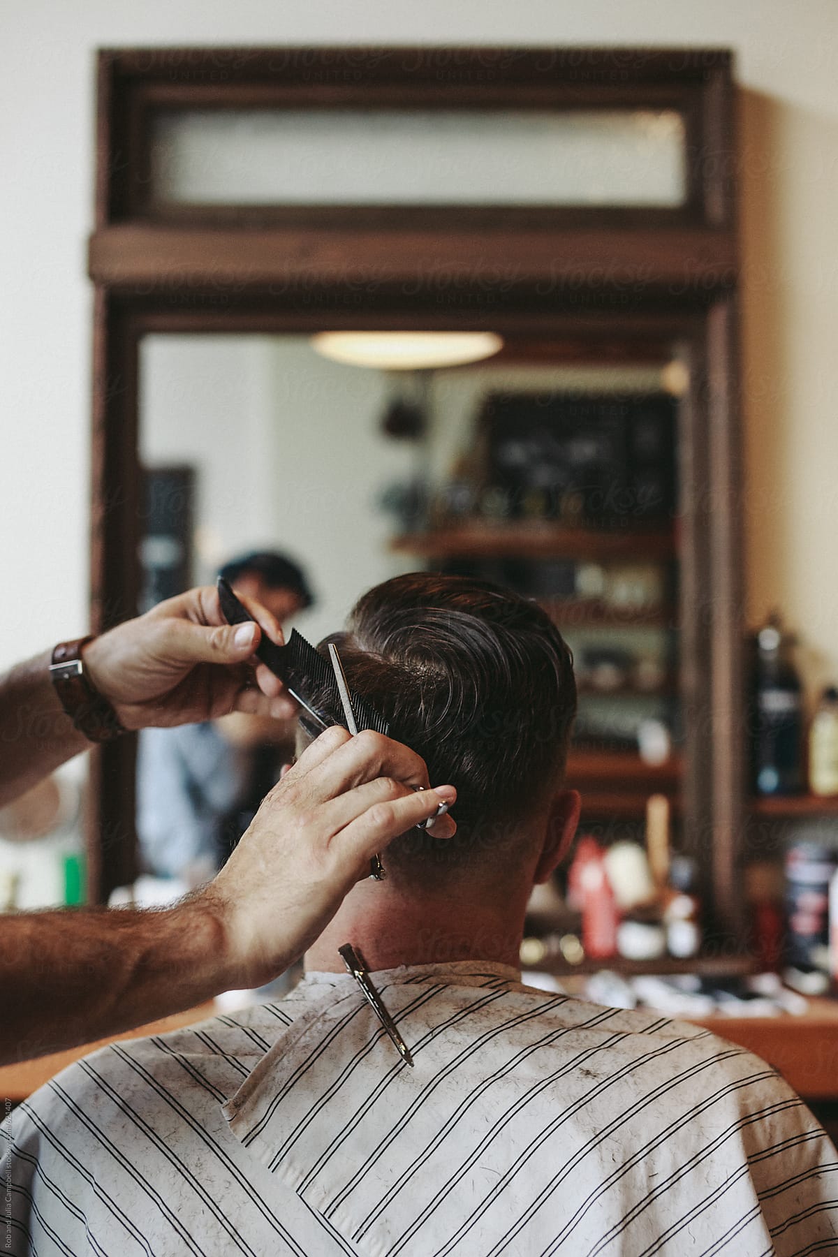 Detail shot of barbers hands working with scissors on classic mens haircut