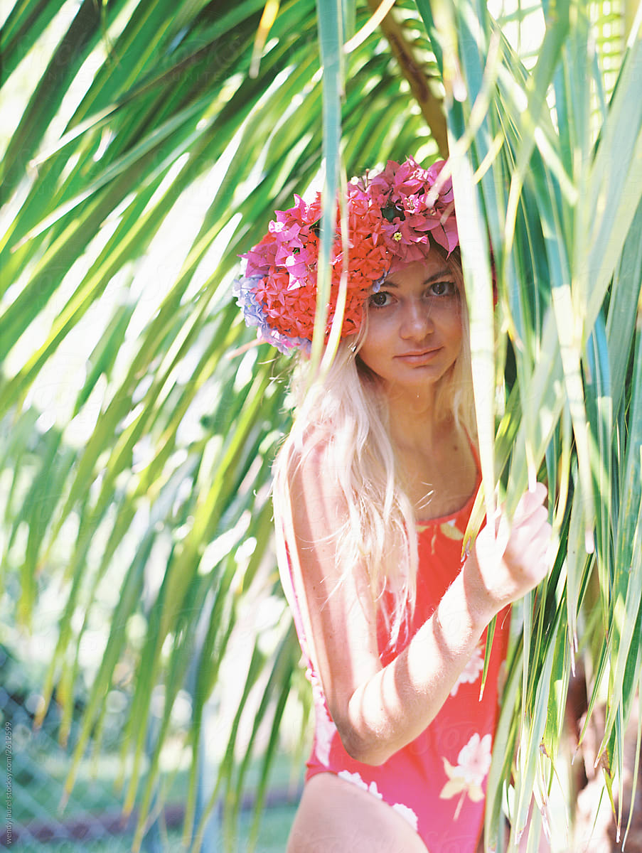 Blonde woman with floral crown and palm trees and flowers being happy and joyful with rainbow stripes