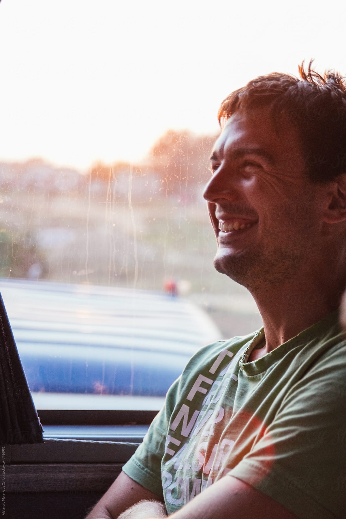 Young Man Laughing Traveling In A Bus At Sunset Del Colaborador De Stocksy Alejandro Moreno