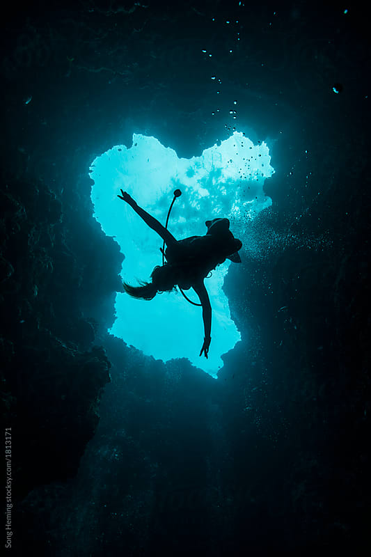 A young female scuba diver diving down to the blue hole