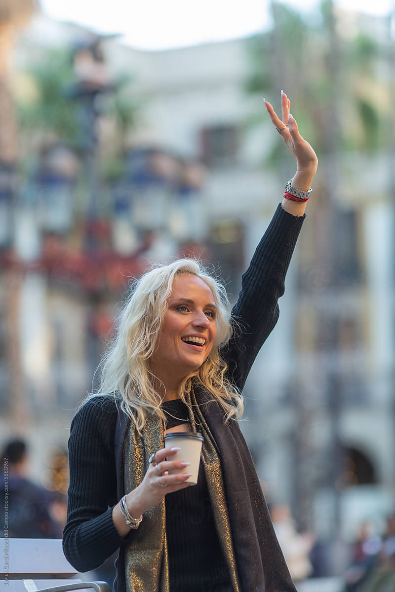 Stylish woman waving with coffee