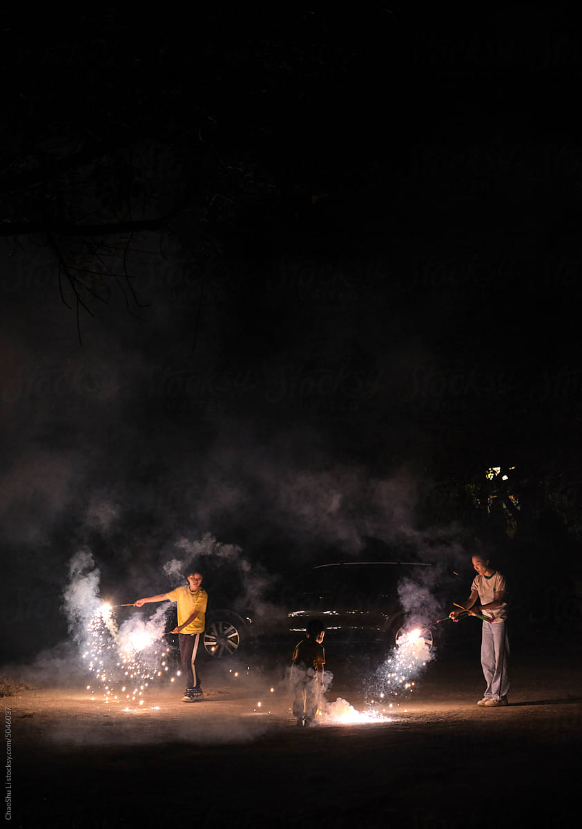 Asian family, having fun with fireworks outdoors at night in nature