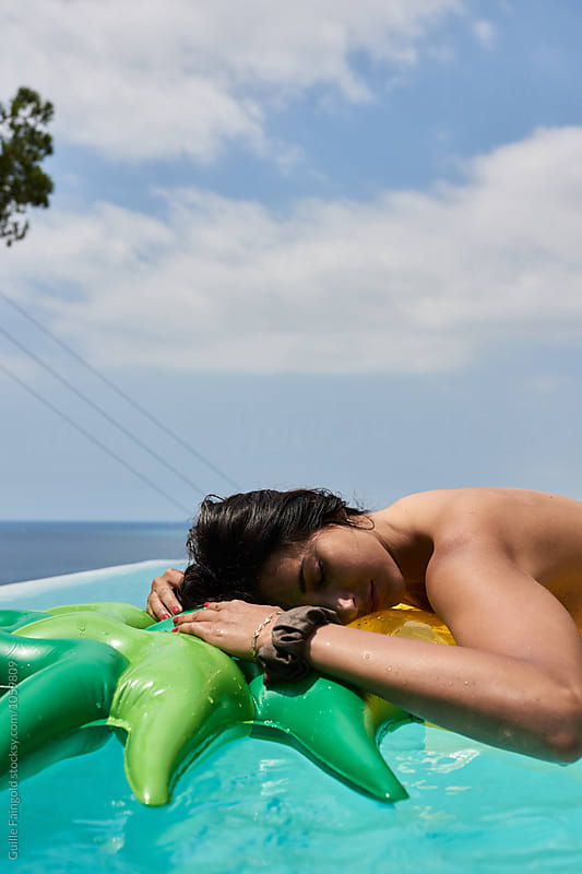 Relaxed brunette sunbathing on inflatable in pool