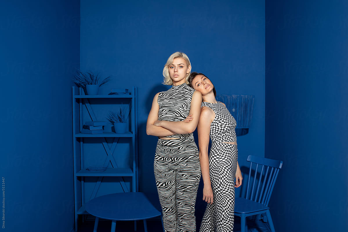 Conceptual portrait with two fashionable girls in a blue interior