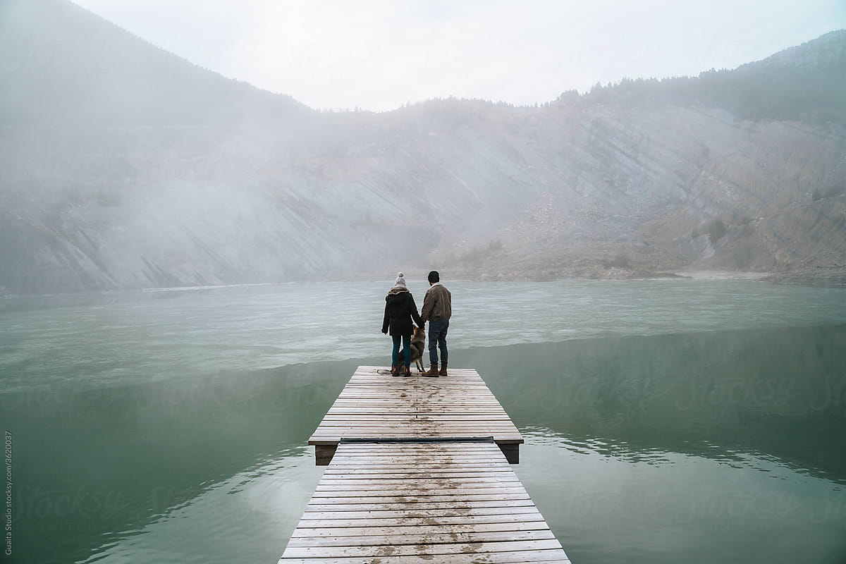 Couple on wooden dock in frozen lake in mountain