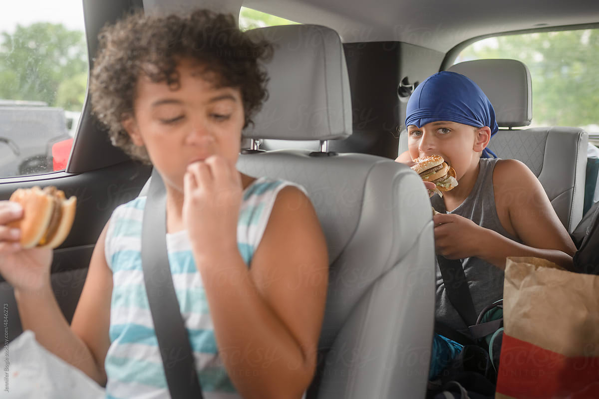 Boy takes huge bite of burger in car