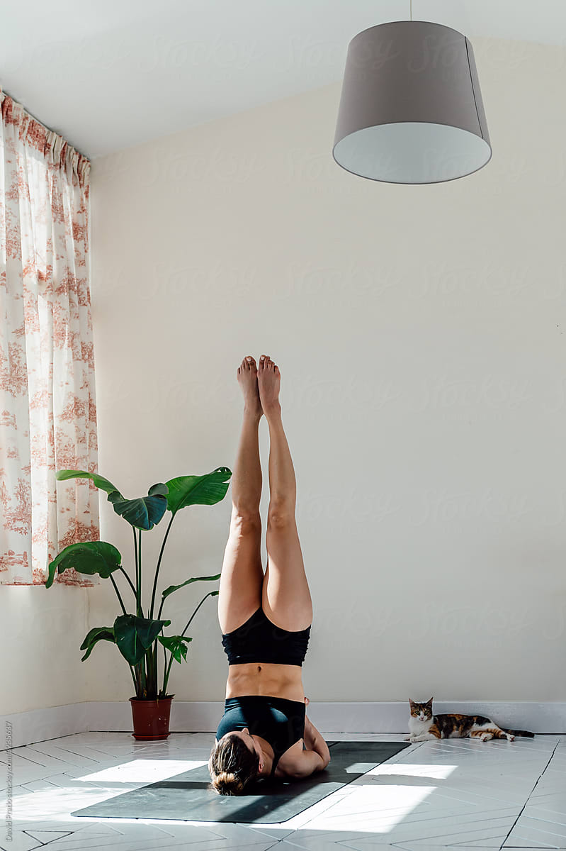 Crop woman doing handstand at home