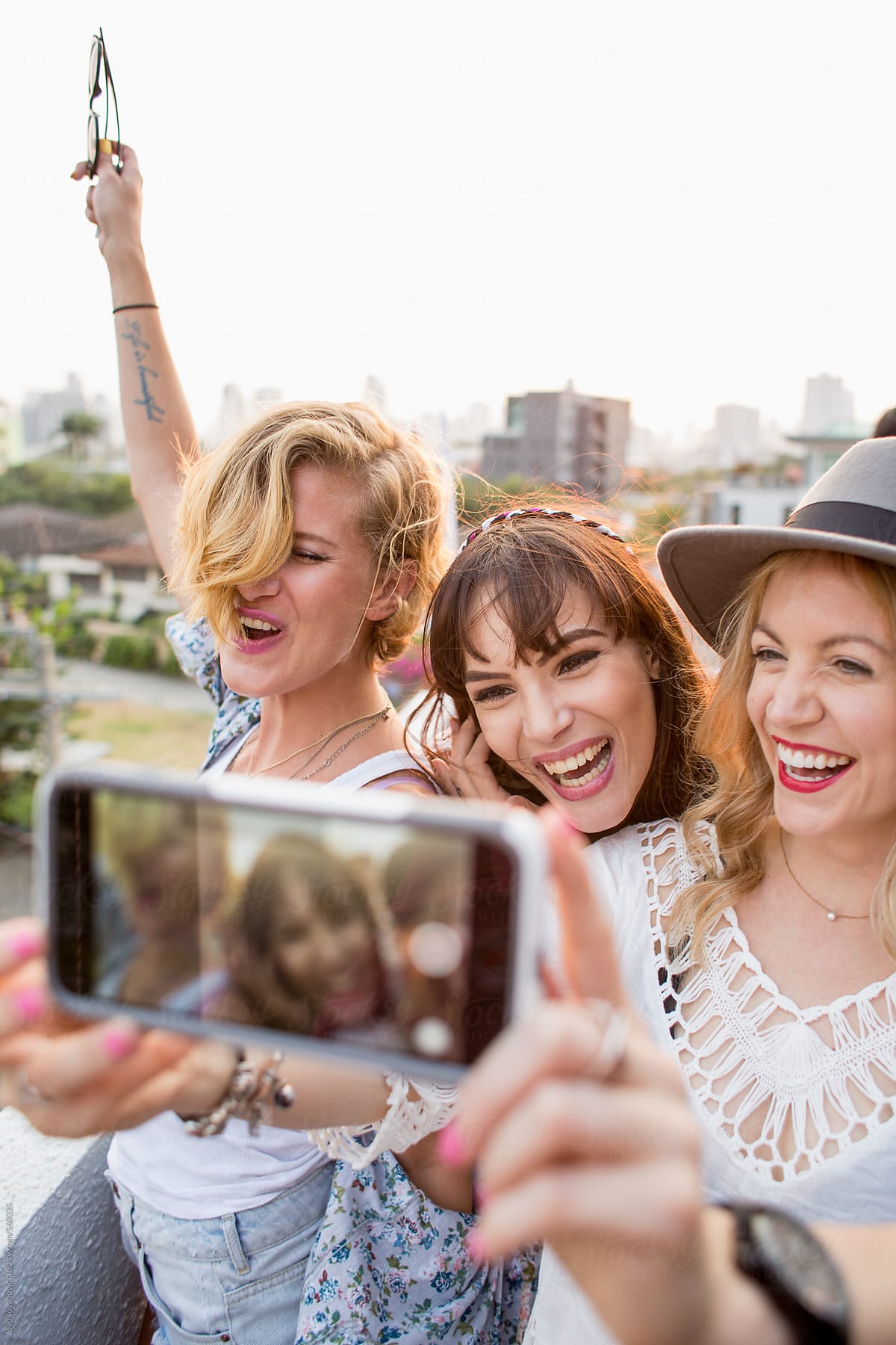 Three Smiling Girlfriends Take A Selfie On A Rooftop By Stocksy 