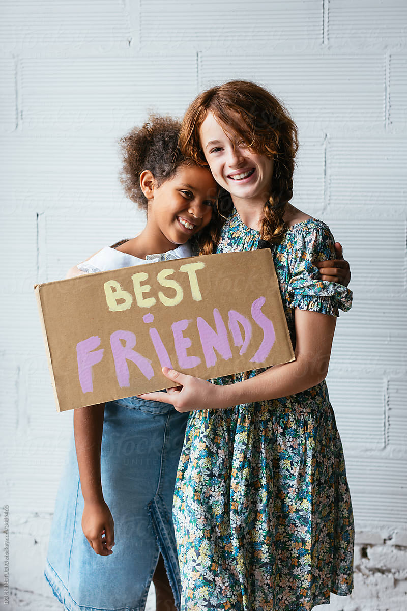 Delighted multiethnic best friends with poster